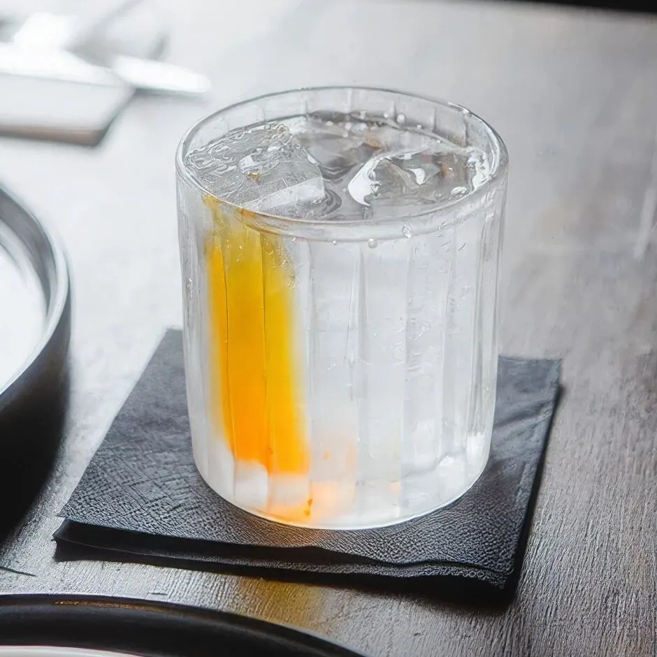 A clear beverage glass with ice, a typical gum arabic emulsion application