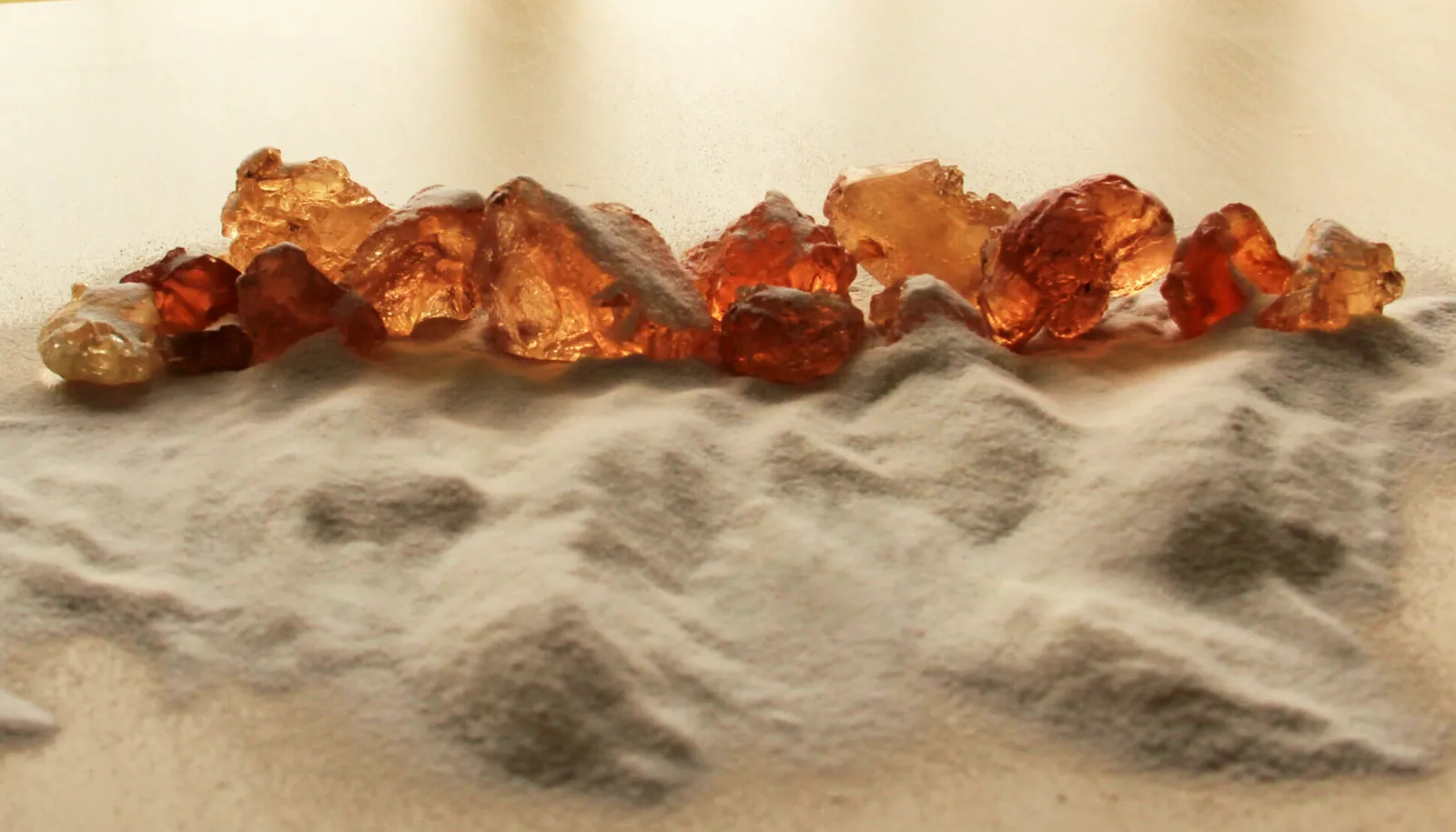 Raw amber gum arabic nodules on a dune of milled gum powder